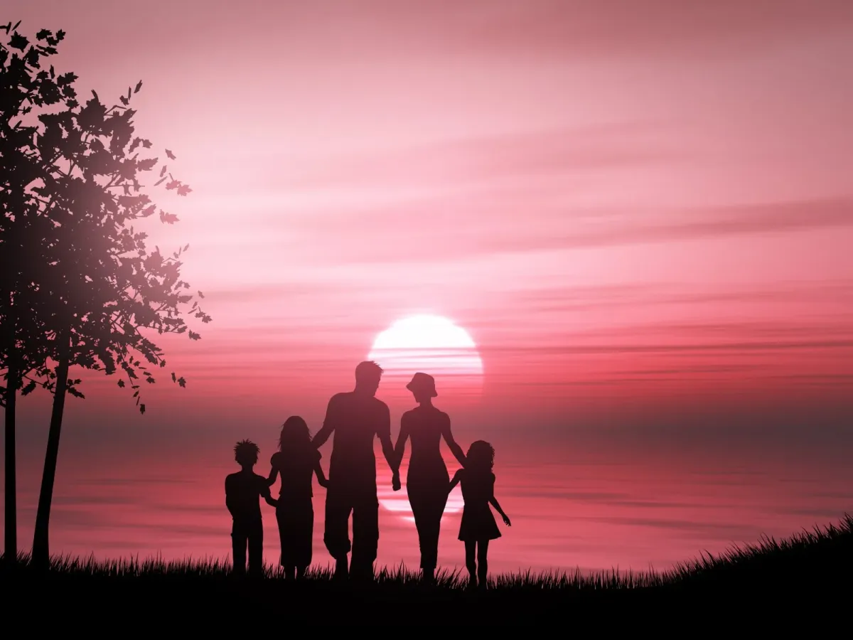Silhouette of a family of five holding hands by the sea at sunset